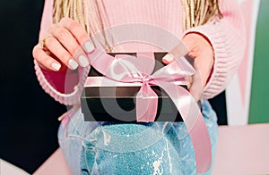Woman`s hands with pink manicure holding black present box