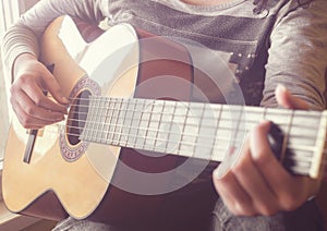 Woman`s hands playing acoustic guitar, close up