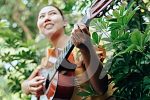 Woman`s hands playing acoustic guitar have fun outdoor, close up