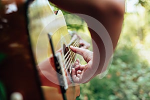 Woman`s hands playing acoustic guitar have fun outdoor, close up