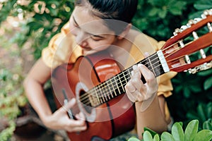 Woman`s hands playing acoustic guitar have fun outdoor, close up