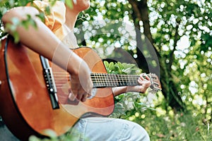 Woman`s hands playing acoustic guitar have fun outdoor, close up