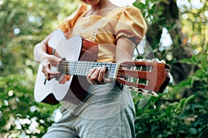 Woman`s hands playing acoustic guitar have fun outdoor, close up