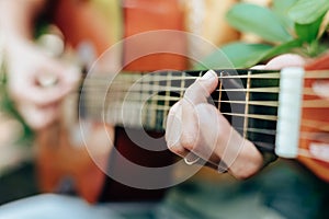Woman`s hands playing acoustic guitar have fun outdoor, close up