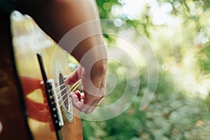 Woman`s hands playing acoustic guitar have fun outdoor, close up