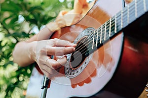 Woman`s hands playing acoustic guitar have fun outdoor, close up