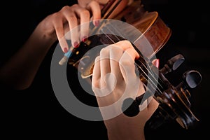 Woman`s hands playing the violin in a black background
