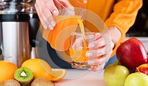 Woman`s hands pour freshly prepared tasty and healthy juice into a glass. Healthy fruit juices at home. Close-up. Selective focus