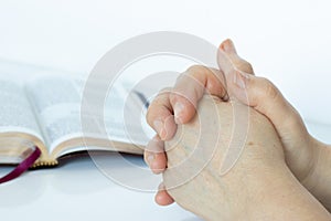 Woman`s hands praying with open Holy Bible Book on white background