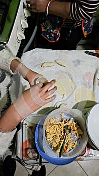 Woman's hands prepare molotes, corn dough filled with meat, a typical Mexican dish in a cookery in Mexico