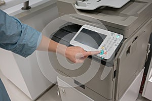 Woman`s hands pressing button on copy machine in office