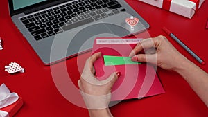 Woman's hands put a valentine's love postcard with green screen chroma key in the festive envelope. Top view of red