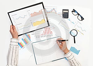 A woman`s hands record data from a report with graphs