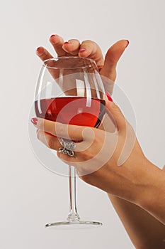 Woman's hands with red manicure holding a glass of red wine