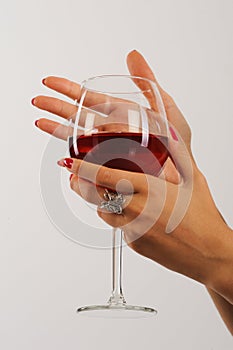 Woman's hands with red manicure holding a glass of red wine