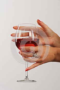 Woman's hands with red manicure holding a glass of red wine