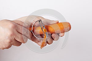 Woman`s hands removing the outer layer of a carrot with a julienne cutter