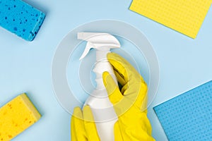 A woman\'s hands in a rubber yellow glove hold a spray cleaner. Cleaning concept. Top view