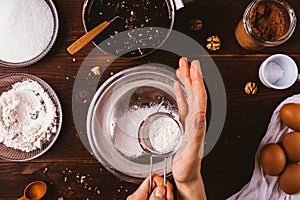 Woman's hands sift flour into bowl