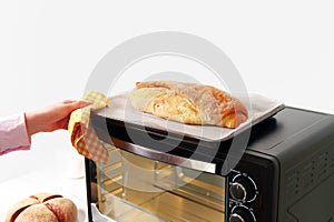 Woman's hands taking fresh bakery out of mini oven close up