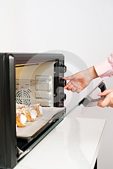 Woman& x27;s hands taking fresh bakery out of mini oven close up