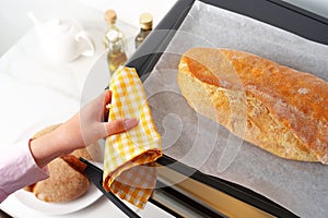 Woman's hands taking fresh bakery out of mini oven close up