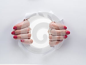 Woman`s hands tearing the hole on a paper.