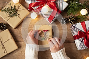 Woman`s hands tying the bow on vintage present on rustic background. Festive backdrop for winter holidays: Birthday, Valentines