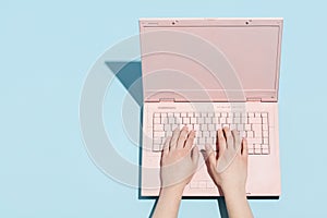 Woman`s hands typing on a pastel pink keyboard