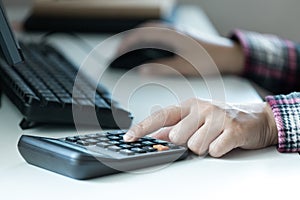 Woman`s hands using calculator on table