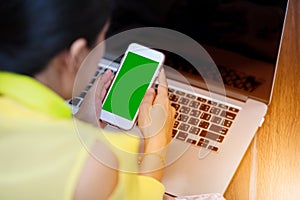 Woman`s hands using cell phone and laptop computer on floor wood