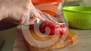 woman's hands using kitchen knife cutting fresh tomato on wooden cutting board. Healthy eating. Sliced tomato. food