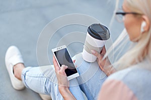 Woman`s hands using phone and holding paper cup with coffee. Teen hipster online internet consept