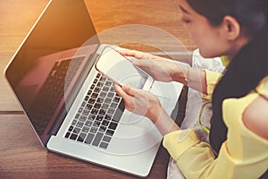 Woman`s hands using smart phone and laptop computer on floor woo