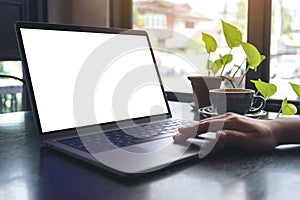 A woman`s hands using and touching laptop touchpad with blank white desktop screen with coffee cup on wooden table in cafe