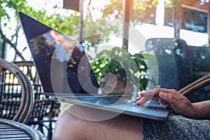 Woman`s hands using and touching on laptop touchpad while sitting in outdoor