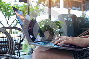Woman`s hands using and typing on laptop keyboard while sitting in outdoor