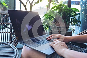 Woman`s hands using and typing on laptop touchpad while sitting in the outdoors