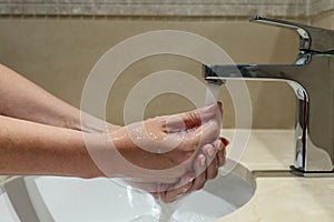Woman`s hands washing under the faucet or water tap in a bathroom photo