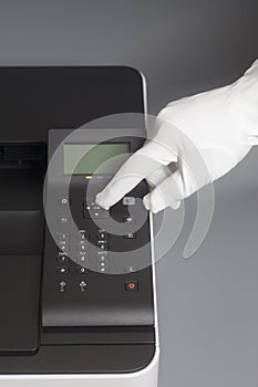 Woman`s hands in white glove pressing button on control panel color laser printer