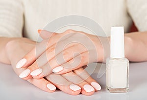 woman's hands with white nail varnish bottles