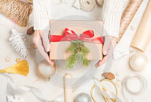 Woman`s hands wrap christmas holiday handmade present in craft paper with twine ribbon.