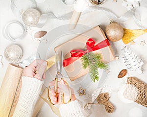 Woman`s hands wrap christmas holiday handmade present in craft paper with twine ribbon.