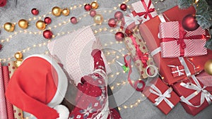 The woman's hands wrap gifts in Christmas paper with diligence and tenderness, creating a magical mood and surprise