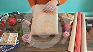 Woman s hands wrapping Christmas gift on dark wooden background.