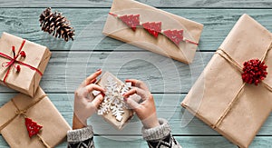 Woman`s hands wrapping christmas holiday present with craft twin