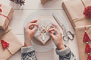 Woman`s hands wrapping christmas holiday present with craft twine