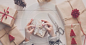 Woman`s hands wrapping christmas holiday present with craft twine