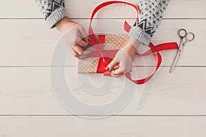 Woman`s hands wrapping christmas holiday present with red ribbon