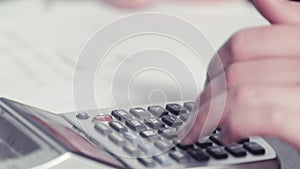 Woman's hands writing with a pencil and typing on a calculator